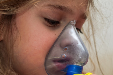Little girl child makes inhalation with mask on face	
