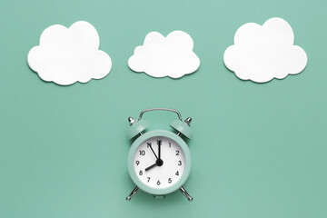 Classic round alarm clock and white clouds on the mint green background.