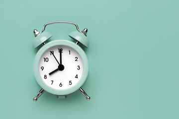 Classic round alarm clock on the mint green background.