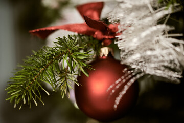 Festive christmas background with red bauble and white tinsel on branch of fir tree.