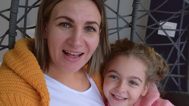 Close up video of a mother and daughter speaking on camera with someone during online meeting