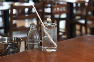 Fresh water in glass with paper drinking straw on restaurant background. Concept for reduce plastic pollution and support green eco friendly products.