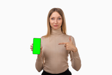 Note that. Pretty young blond woman is pointing finger at mobile phone blank screen in her hand