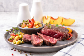 Fried beef steak with peach fruit salsa, tomato and chili.