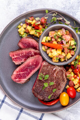 Fried beef steak with peach fruit salsa, tomato and chili.