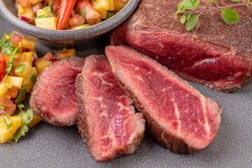 Fried beef steak with peach fruit salsa, tomato and chili.