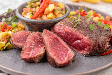 Fried beef steak with peach fruit salsa, tomato and chili.