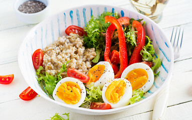 Breakfast oatmeal porridge with green herbs, boiled egg, tomatoes and paprika. Healthy balanced food.