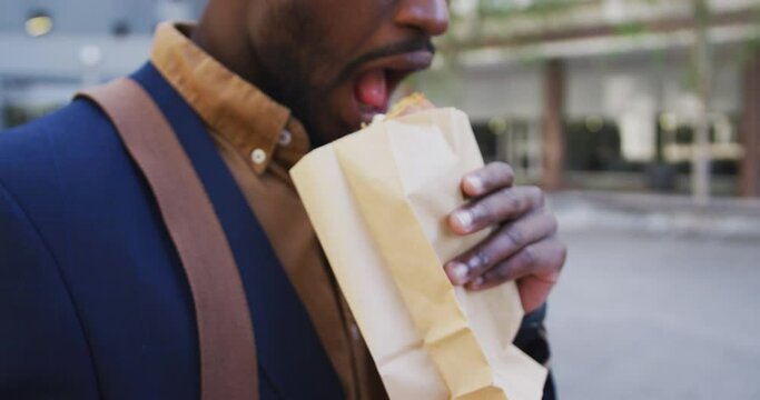 African american businessman eating sandwich in city street