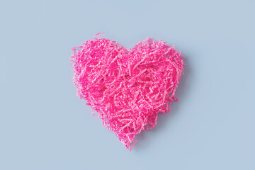 Shape of pink heart like tangle of packaging material, greeting card on blue background