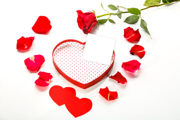 Rose and Postcard copy space in a box in the shape of a heart on a white background with rose petals in the middle.