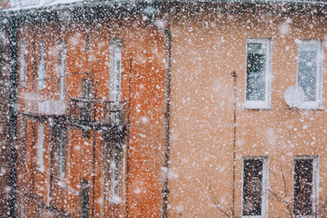 Snowfall in the city. Defocused heavy snowfall, yellow residential building blured in the background. Heavy snow concept