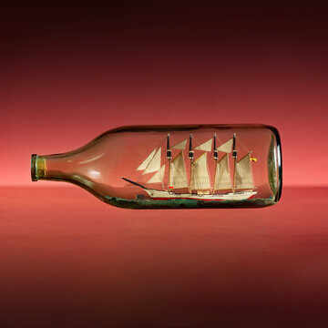Un barco de ensue&ntilde;o en una botella sobre fondo rojo, concepto de imaginaci&oacute;n y ambici&oacute;n.
