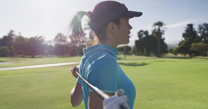 Portrait of female caucasian golf player standing with golf club around her back at golf course