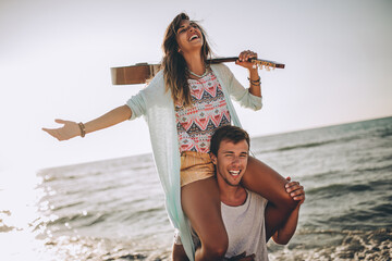 Young man giving piggyback ride to girlfriend on beach.