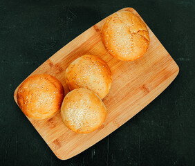 Flat lay, top view of home made buns with sesame seeds on a bambus wood plate