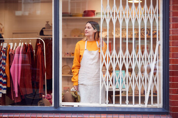Female Small Business Owner Pushing Back Security Grill And Opening Shop