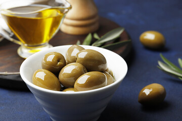 Composition of green olives, oil, spices on a blue  background. Space for text.