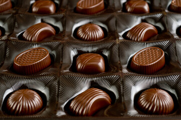 Assorted chocolates lying in a box. Background for products from chocolate and sweets. Dark chocolate.