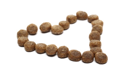 Dog food, dry round granules in heart shape isolated on white background