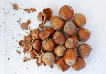 Hazelnuts, some of them shelled, on a white background.