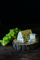 
blue cheese on a wooden frame on a wooden background with white grapes in rustic style