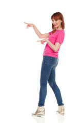Happy Casual Young Woman Is Pointing And Smiling.