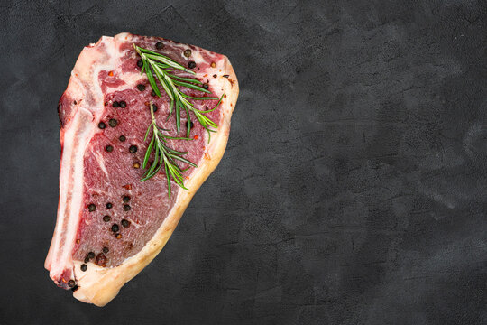 Steak with rosemary and pepper on a black background.