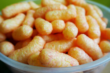 close up lots of strawberry corn sticks in a white plastic bowl side view at a children's party