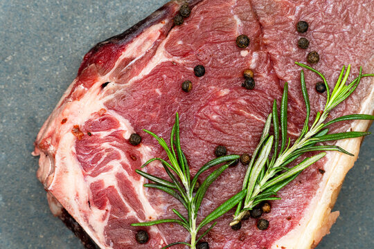 Steak with rosemary and pepper on a black background.