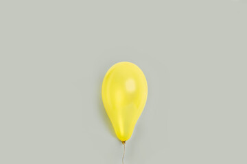 Globo amarillo inflado sobre un fondo gris liso y aislado. Vista de frente. Copy space