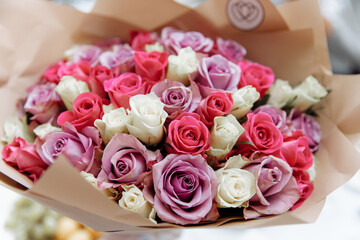 Delicate bouquet of multi-colored roses in craft paper.