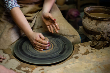 Creating a jar or vase Master crock. The sculptor in workshop makes jug out of earthenware closeup. artisan woman makes a pot on a potter's wheel from clay close-up