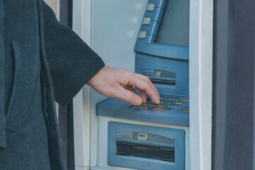 Man's hand on the ATM keyboard on the city street