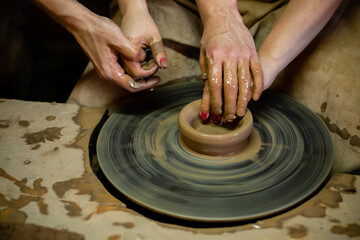 Pottery classes, student making clay pot on wheel. Close-up of dirty hands, sculpting clay crockery pottery training