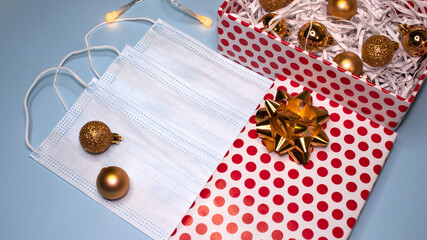 Gift box decorated with a bow with balls and a mask on a blue background. Top view