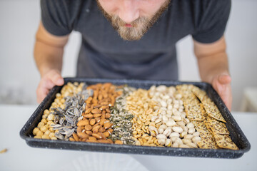 Male hand holding a black tray of nuts and seeds