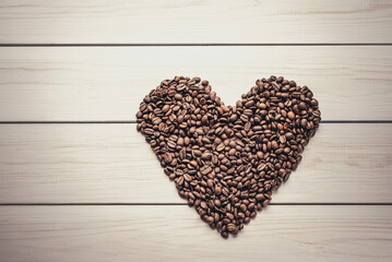 texture of coffee beans in heart shape on white wooden surface