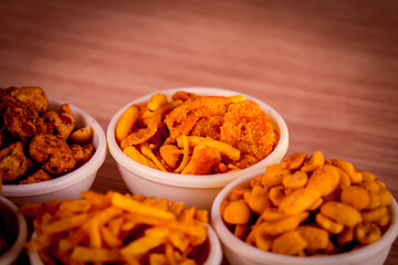 mix chavad,Indian morning or tea-time snacks like bhakharvadi , chivda, farsan, mixture, shing bhujia, bakarwadi etc served in white wooden box