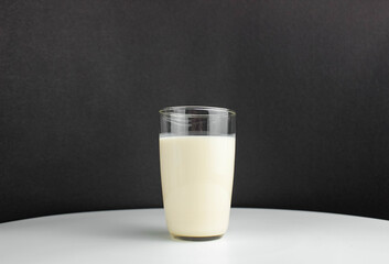 Milk in a clear glass on a black and white background.