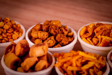 indian namkeen on wooden table,Indian Namkeen or snacks in white bowl on wooden background, close up of indian Namkeen snacks beautiful footage,Sev murmura,chanadal,shing bhujia,mix chavana