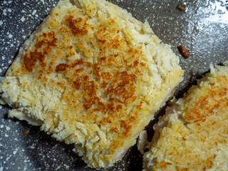 Schnitzels with a crispy bread crust are fried in a pan. The oil glistens on the surface of the pan. Food background with appetizing cutlets.