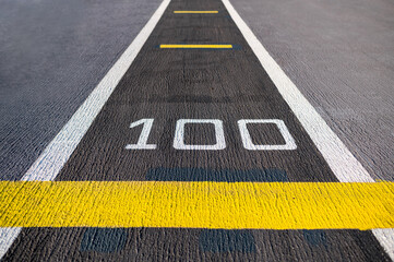 Number 100 on flight deck of aircraft carrier. Airplane runway on military navy ship. Aviation concept