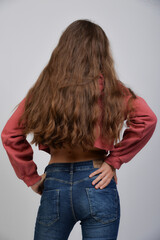 frau teenager stehend po jeans lange lockige braune haare