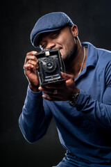 Concentrated afro american man taking photo on camera. Portrait of a man isolated on black background.