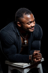 Sexy afro american bodybuilder with unbuttoned dark shirt. Athlete poses to the camera. Strong muscular body.