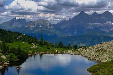 colorful hikers on the shore from a mountain lake in the summer
