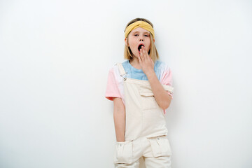 Young teenager girl blonde yawns, covering her mouth with her hand. 