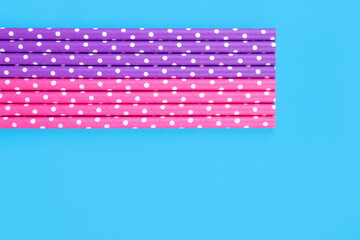 Pink and purple straws on light blue background