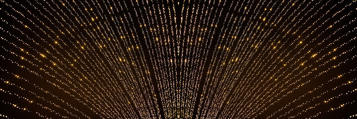 Blurred gold illuminations texture on holiday background. Design element golden explosion of confetti. Abstract glitter texture on a black background.